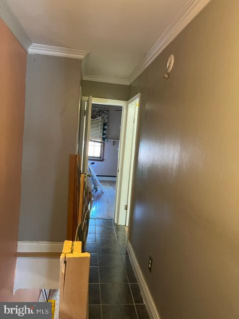 hallway featuring crown molding and dark tile floors