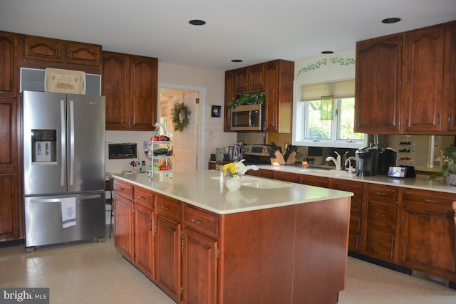 kitchen featuring a kitchen island, light tile floors, appliances with stainless steel finishes, and sink