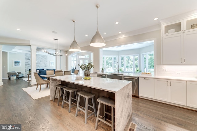 kitchen with hanging light fixtures, a kitchen island, dishwasher, dark hardwood / wood-style flooring, and white cabinets