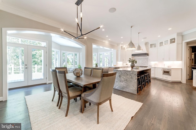 dining room with french doors, dark hardwood / wood-style flooring, a notable chandelier, and ornamental molding