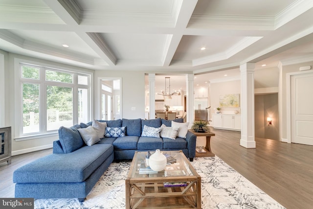 living room with a notable chandelier, decorative columns, coffered ceiling, and light hardwood / wood-style floors