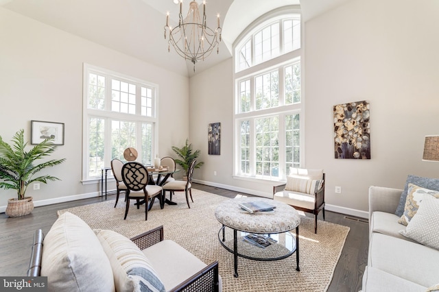 living room with dark hardwood / wood-style flooring, a high ceiling, a chandelier, and a healthy amount of sunlight