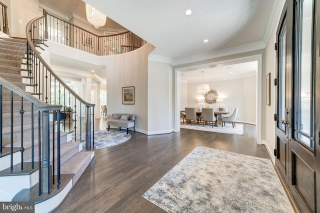 foyer featuring dark hardwood / wood-style floors, ornamental molding, a healthy amount of sunlight, and a chandelier