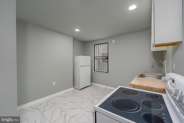 kitchen with range, white refrigerator, white cabinetry, light tile floors, and sink