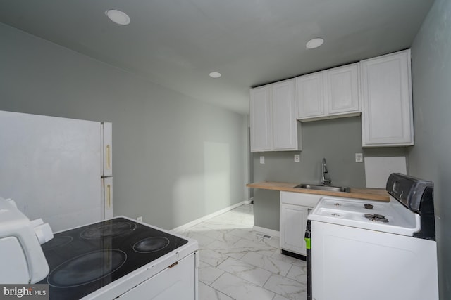 kitchen featuring light tile floors, stove, washer / dryer, white cabinets, and sink