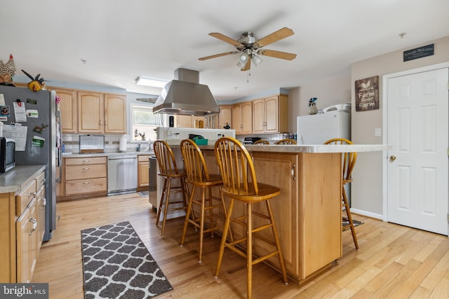 kitchen with ceiling fan, island range hood, light hardwood / wood-style floors, and a kitchen breakfast bar