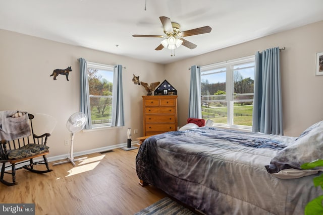 bedroom with multiple windows, light hardwood / wood-style flooring, and ceiling fan