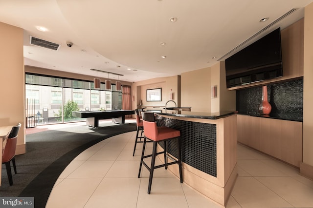 kitchen featuring a kitchen breakfast bar, plenty of natural light, decorative light fixtures, and light tile flooring