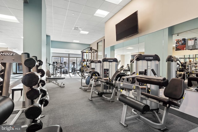 exercise room with a paneled ceiling and carpet flooring