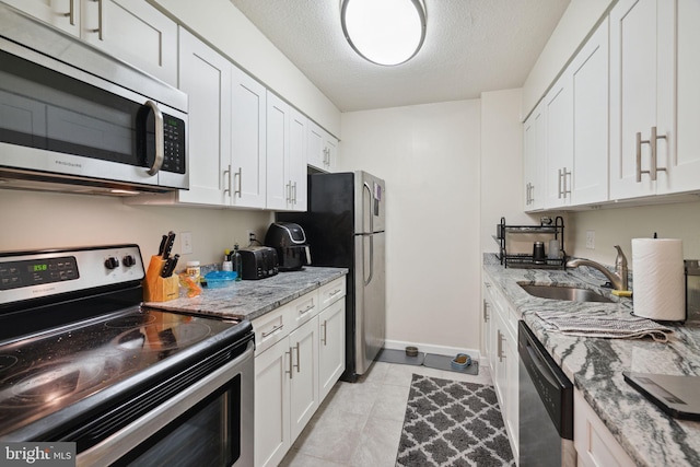 kitchen featuring sink, stainless steel appliances, light tile floors, white cabinets, and light stone counters