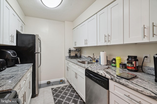 kitchen with white cabinetry, stainless steel dishwasher, light tile floors, light stone countertops, and sink