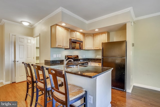 kitchen featuring a kitchen bar, kitchen peninsula, light hardwood / wood-style floors, and black appliances