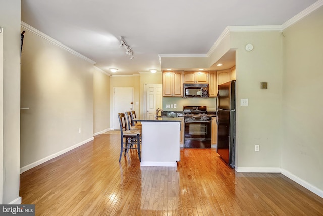 kitchen featuring a breakfast bar, rail lighting, light wood-type flooring, black appliances, and ornamental molding