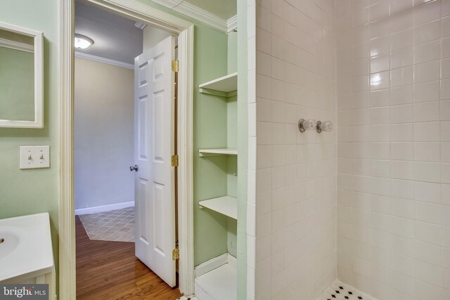 bathroom with crown molding, tiled shower, and hardwood / wood-style floors