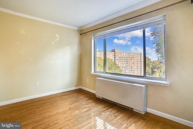 spare room with light hardwood / wood-style floors, ornamental molding, and radiator