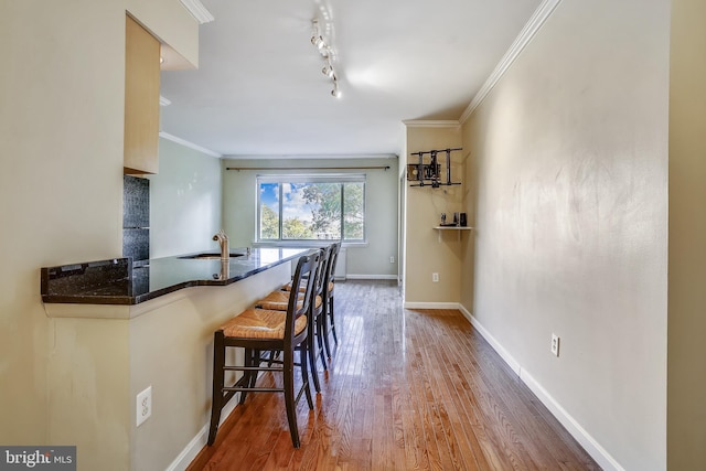 kitchen featuring a kitchen breakfast bar, sink, track lighting, and hardwood / wood-style floors