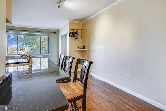 dining space featuring crown molding, rail lighting, and wood-type flooring