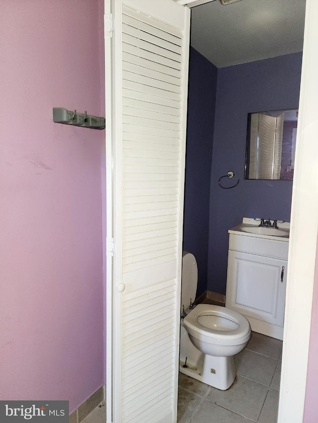 bathroom with tile flooring, toilet, and vanity