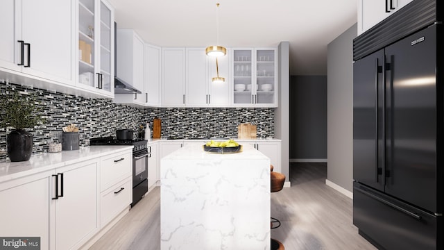 kitchen with pendant lighting, light hardwood / wood-style flooring, premium appliances, light stone countertops, and a center island