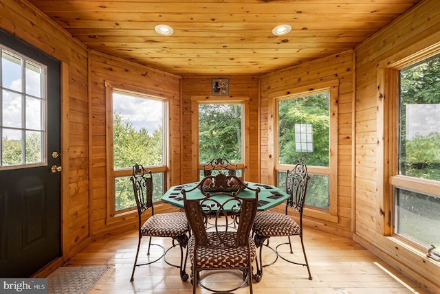 dining room with wood walls, light wood-type flooring, and wood ceiling