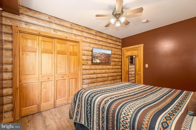 bedroom with light hardwood / wood-style floors, rustic walls, a closet, and ceiling fan