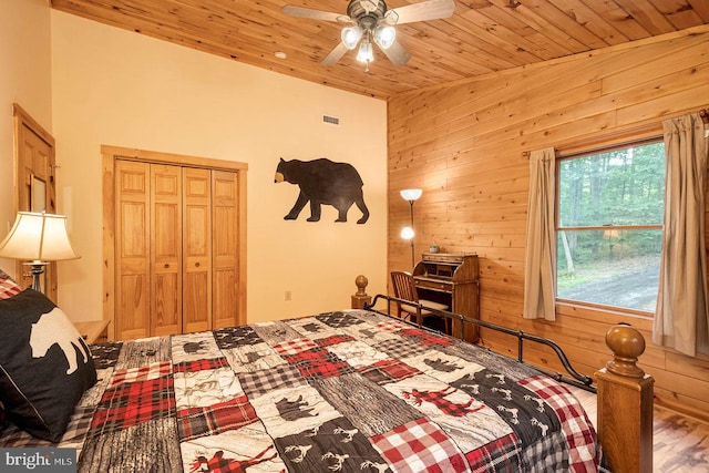 bedroom with ceiling fan, a closet, wooden walls, hardwood / wood-style flooring, and wooden ceiling