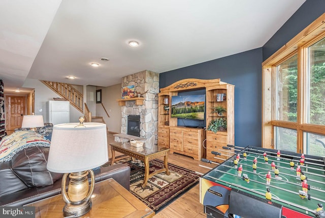 living room featuring a stone fireplace and light wood-type flooring