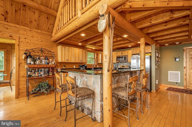 kitchen with vaulted ceiling with beams, light wood-type flooring, stainless steel appliances, kitchen peninsula, and wood ceiling