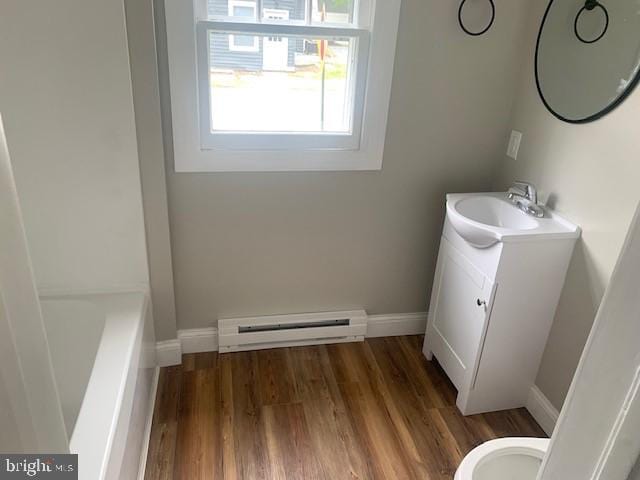 bathroom featuring toilet, vanity, hardwood / wood-style flooring, and a baseboard heating unit