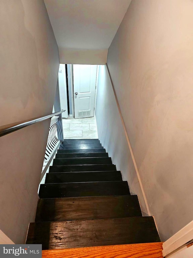 stairway featuring dark tile flooring