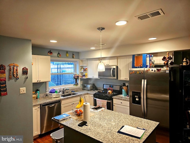 kitchen with decorative light fixtures, sink, stainless steel appliances, white cabinets, and light stone counters