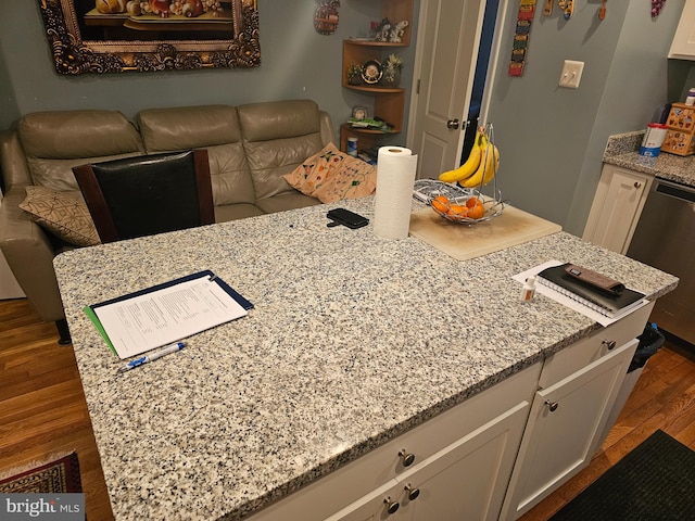 kitchen featuring light stone countertops, white cabinetry, stainless steel dishwasher, and dark hardwood / wood-style flooring