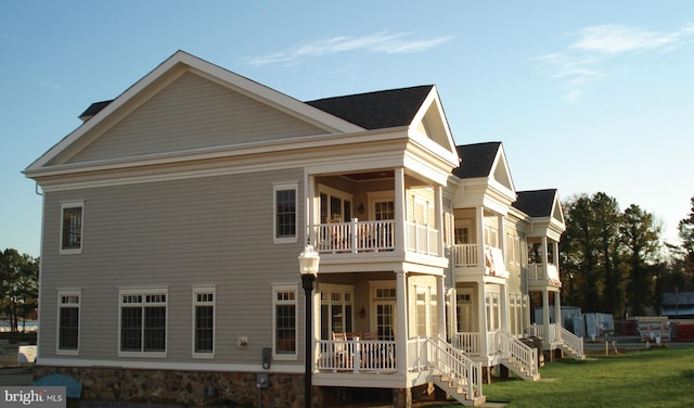 back of property featuring a lawn and a balcony