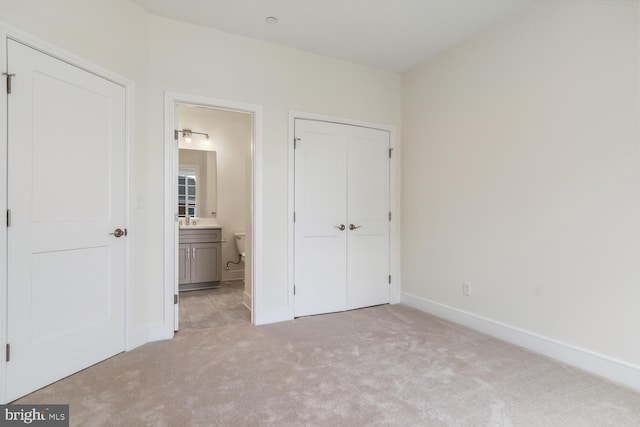 unfurnished bedroom with ensuite bathroom, sink, and light carpet