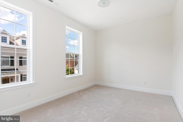 unfurnished room featuring a wealth of natural light and light carpet