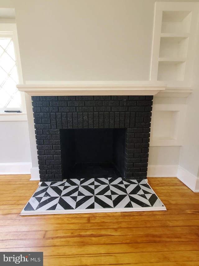 details with built in shelves, light wood-type flooring, and a fireplace