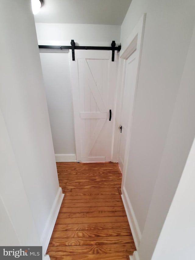 hallway with a barn door and light hardwood / wood-style flooring