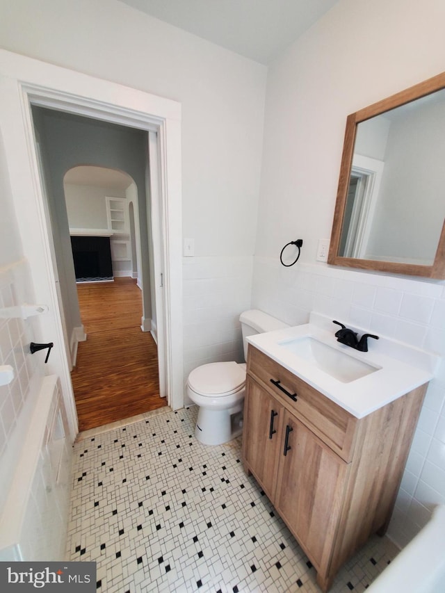 bathroom with vanity, backsplash, tile walls, tile floors, and toilet