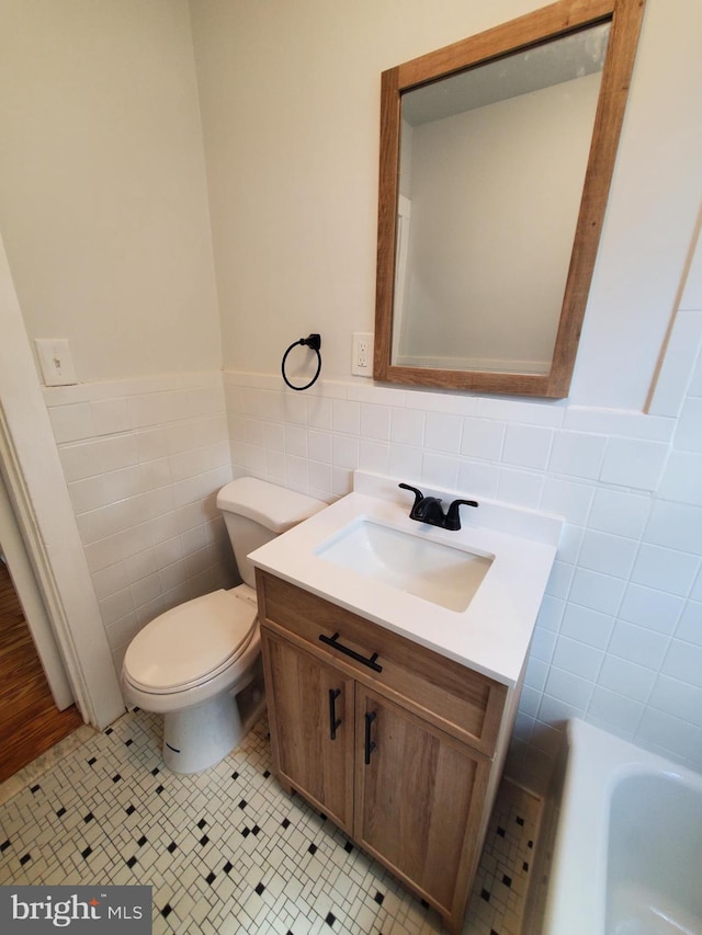 bathroom with tile walls, toilet, vanity, and tile floors