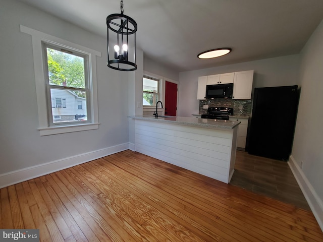 kitchen featuring light wood-type flooring, white cabinetry, a chandelier, and black appliances