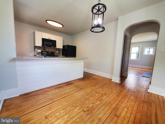 kitchen with backsplash, light hardwood / wood-style floors, white cabinets, and black appliances