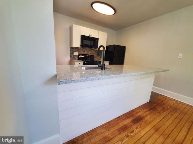 kitchen with backsplash, dark wood-type flooring, light stone counters, and black appliances