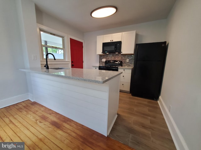 kitchen featuring light wood-type flooring, sink, light stone countertops, black appliances, and white cabinets