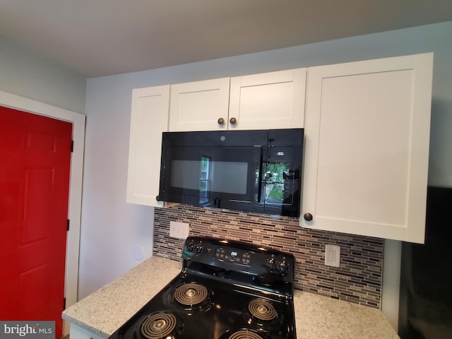 kitchen with white cabinets, light stone countertops, backsplash, and range