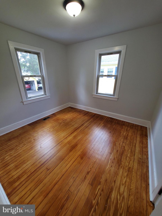 spare room featuring dark hardwood / wood-style flooring and a healthy amount of sunlight