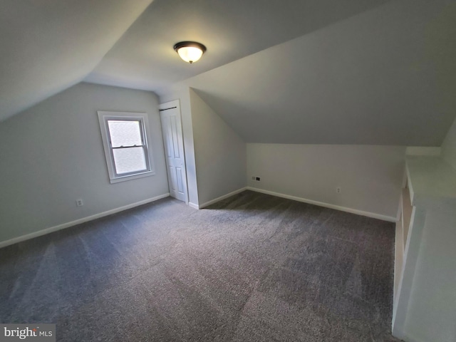 bonus room with vaulted ceiling and dark colored carpet