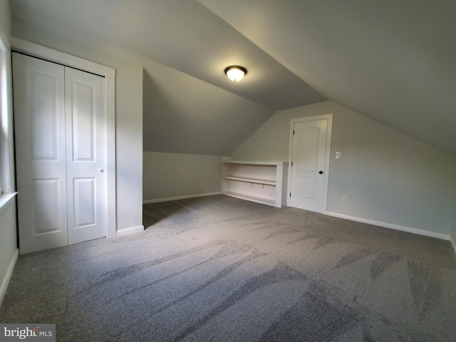 bonus room with dark colored carpet and vaulted ceiling