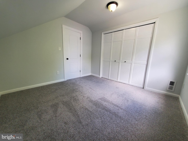 unfurnished bedroom featuring lofted ceiling, a closet, and carpet