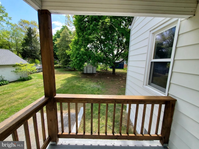 wooden terrace featuring a lawn and a storage shed