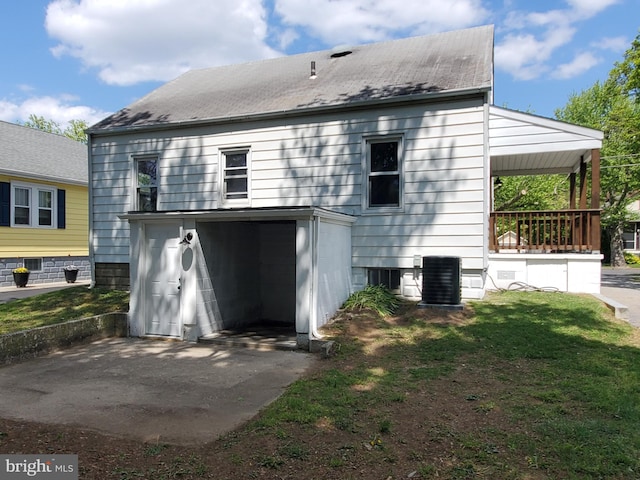 rear view of house featuring central AC and a lawn